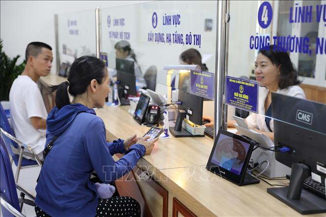 Công chức tại Điểm tiếp nhận,phục vụ hành chính công phường Kim Liên tiếp nhận và xử lý thủ tục hành chính cho người dân . Ảnh: Quốc Lũy - TTXVN