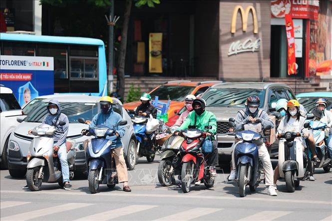 Khẩu trang, áo chống nắng là những thứ không thể thiếu khi tham gia giao thông. Ảnh: Lê Đông - TTXVN