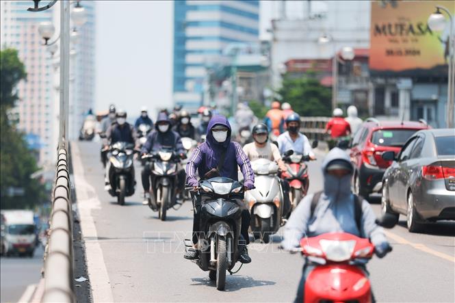 Khẩu trang, áo chống nắng là những thứ không thể thiếu của người dân khi tham gia giao thông. Ảnh: Lê Đông - TTXVN