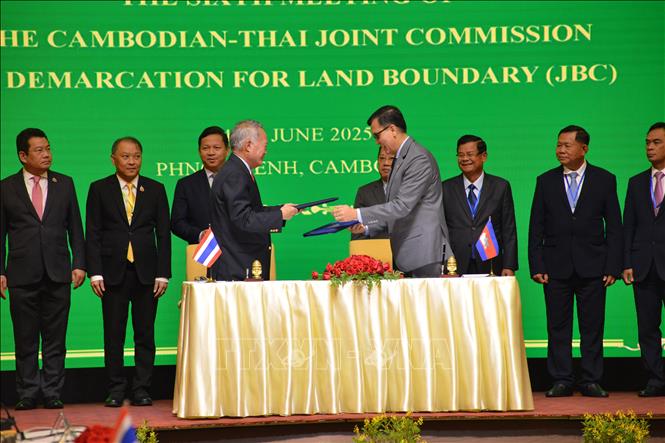 Bộ trưởng phụ trách Ban thư ký Nhà nước về các vấn đề biên giới của Campuchia, ông Lam Chea (phải, phía trước) và Chủ tịch Ủy ban biên giới chung của Bộ Ngoại giao Thái Lan Prasas Prasasvinitchai (trái, phía trước) trao đổi biên bản thỏa thuận của Ủy ban Biên giới Hỗn hợp tại cuộc họp giữa đại diện hai bên ở Phnom Penh (Cambodia), ngày 15/6/2025. Ảnh: THX/TTXVN