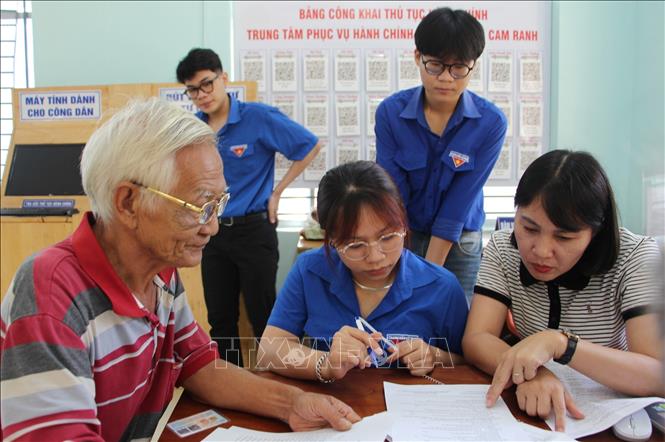 ông Phạm Văn Lắng, trú tại phường Cam Ranh, tỉnh Khánh Hòa được Đội hình thanh niên tình nguyện của phường hướng dẫn thủ tục tại Trung tâm hành chính công. Ảnh: Phan Sáu - TTXVN