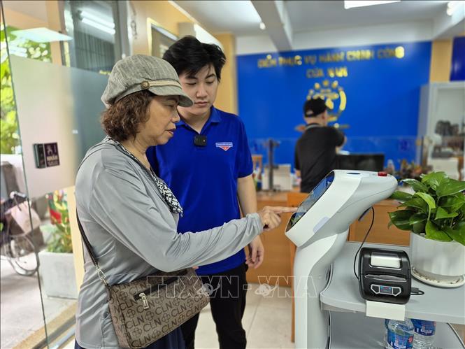 Người dân thực hiện thao tác trên Robot AI hỗ trợ thực hiện các thủ tục hành chính. Ảnh: Nguyễn Thắng - TTXVN 