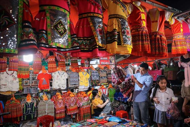 Du khách tìm mua các sản phẩm thổ cẩm địa phương khi đến vui chơi, mua sắm tại chợ đêm Sapa. Ảnh: Hoàng Hiếu - TTXVN