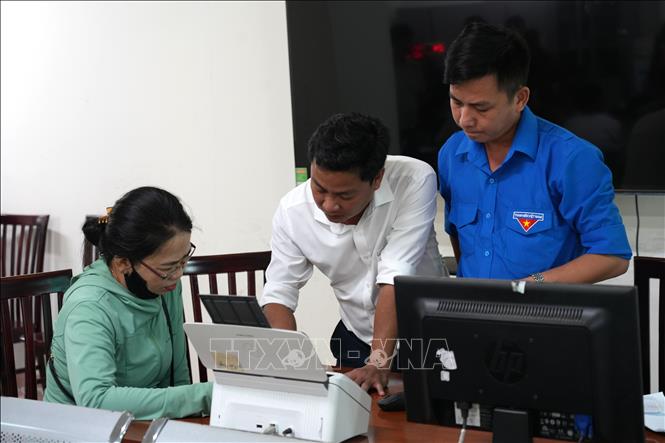 Cán bộ Trung tâm Phục vụ hành chính công và đoàn thanh niên hỗ trợ người dân thực hiện các dịch vụ công trực tuyến. Ảnh: Đinh Hương - TTXVN