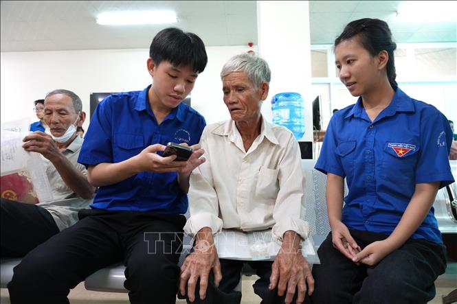 Các đoàn viên thanh niên hướng dẫn người dân cách cài đặt và sử dụng ứng dụng định danh điện tử VNeID cũng như thực hiện các dịch vụ công trực tuyến khác. Ảnh: Đinh Hương - TTXVN