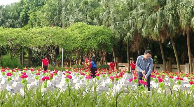 Cán bộ, đoàn viên thanh niên thay mới hoa sen, lọ hoa trên các phần mộ anh hùng liệt sĩ; dọn dẹp và làm sạch đẹp khuôn viên nghĩa trang. Ảnh: TTXVN phát
