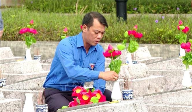 Cán bộ, đoàn viên thanh niên tiến hành thay mới hoa sen trên các phần mộ anh hùng liệt sĩ tại nghĩa trang. Ảnh: TTXVN phát