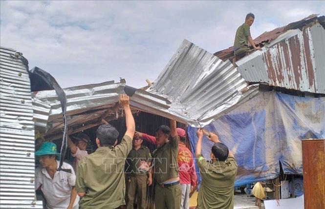 Lực lượng tại chỗ giúp người dân tháo dỡ mái tôn bị gió cuốn sau trận mưa dông. Ảnh: TTXVN phát