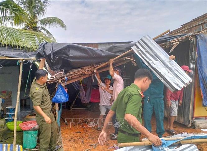 Lực lượng tại chỗ giúp người dân tháo dỡ mái tôn bị gió cuốn sau trận mưa dông. Ảnh: TTXVN phát