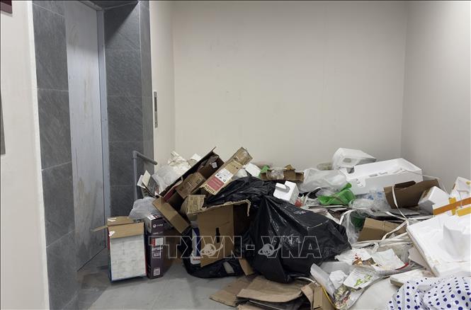 Rác thải bị vứt bừa bãi tràn ra ngay khu vực ra vào thang máy nhưng không được thu gom trong nhiều ngày qua. Ảnh: Thanh Sang -TTXVN