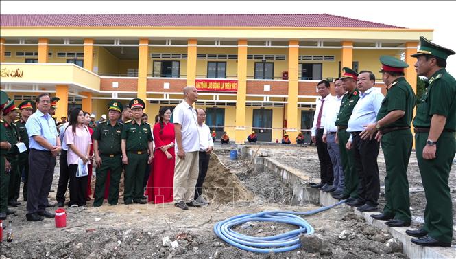 Đoàn công tác của Bộ Quốc phòng  nghe báo cáo tiến độ xây dựng phòng học bán trú cho trẻ em biên giới tại Trường Tiểu học xã Bến Cầu, tỉnh Tây Ninh do Bộ Quốc phòng tài trợ. Ảnh: Minh Phú – TTXVN 