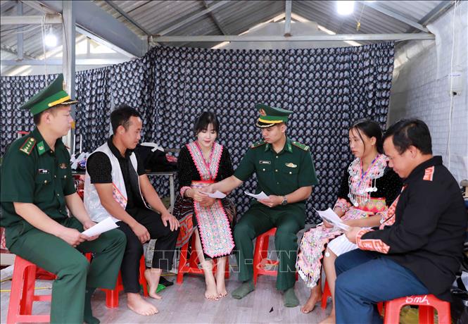 Cán bộ Đồn Biên phòng Sin Suối Hồ phát tờ rơi, hướng dẫn người dân tích cực tố giác tội phạm qua hòm thư tại chợ. Ảnh: Quý Trung - TTXVN