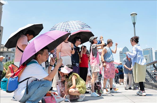Khách du lịch dùng ô che nắng tại Thượng Hải, Trung Quốc ngày 29/6/2025. Ảnh: THX/TTXVN