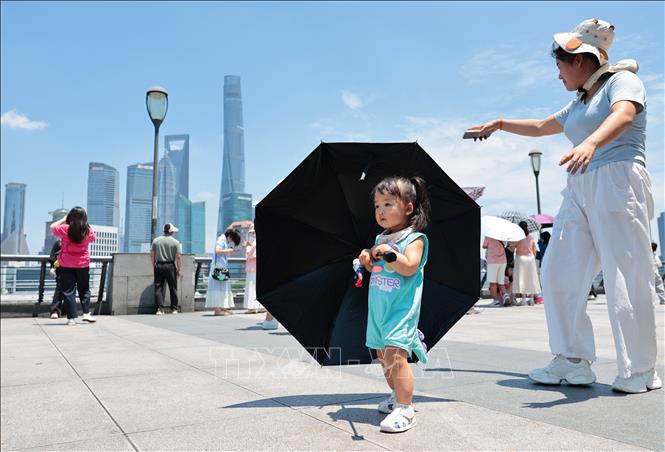 Khách du lịch dùng ô che nắng tại Thượng Hải, Trung Quốc ngày 29/6/2025. Ảnh: THX/TTXVN