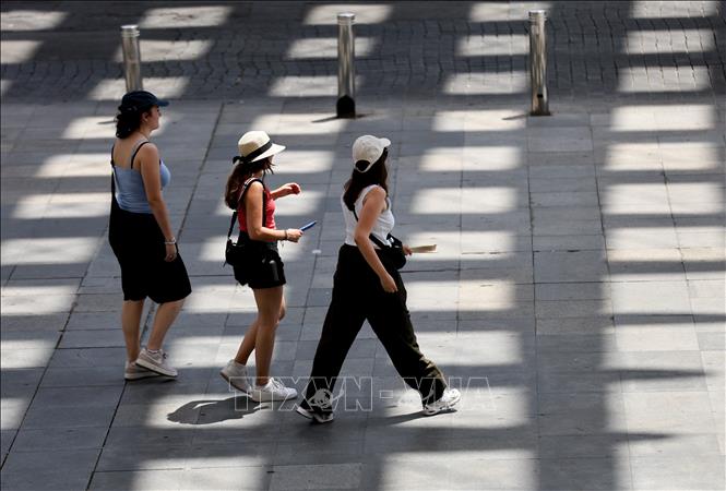 Người dân di chuyển trên đường phố dưới trời nắng nóng tại Seville, Tây Ban Nha. Ảnh: THX/TTXVN