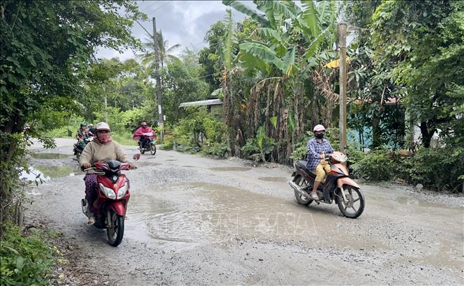 Người dân điều khiển xe máy phải di chuyển chậm, tránh ổ voi, ổ gà trên mặt đường. Ảnh: Thanh Sang - TTXVN