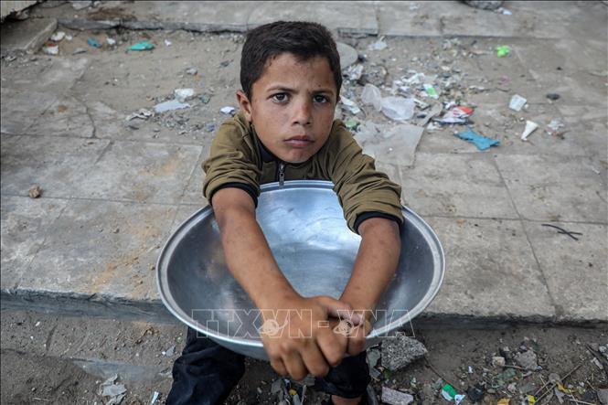 Em nhỏ chờ được phát thực phẩm cứu trợ tại Gaza. Ảnh: THX/TTXVN