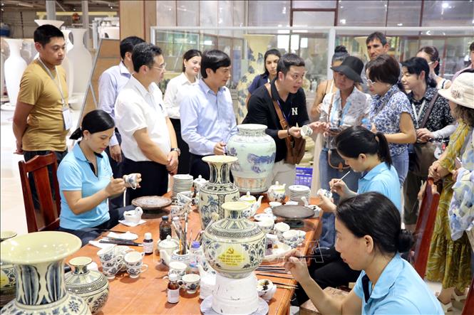 Các vị khách quốc tế thích thú tìm hiểu về quy trình sản xuất gốm Chu Đậu. Ảnh: Mạnh Tú – TTXVN
