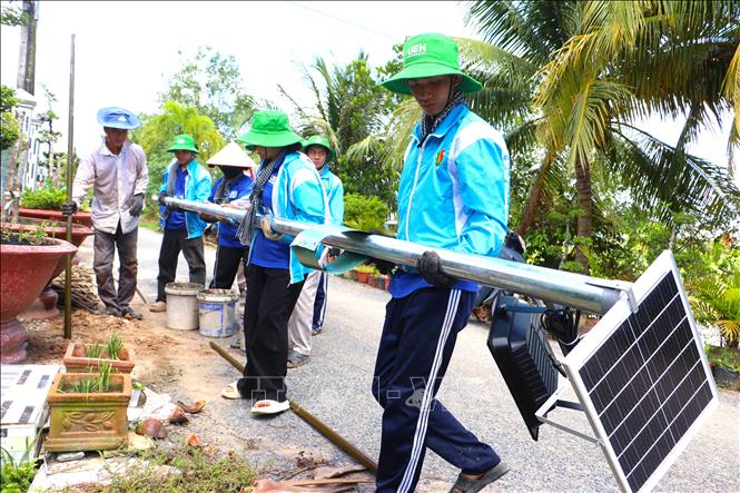 Sinh viên tình nguyện Phân hiệu Đại học Kinh tế Thành phố Hồ Chí Minh tại Vĩnh Long cùng người dân thực hiện công trình đèn đường tại xã Nhơn Phú, tỉnh Vĩnh Long. Ảnh: Lê Thúy Hằng – TTXVN
