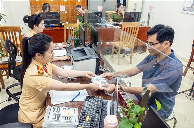Người dân đến nhận biển số xe tại Công an phường Giảng Võ, thành phố Hà Nội. Ảnh: Phạm Kiên - TTXVN