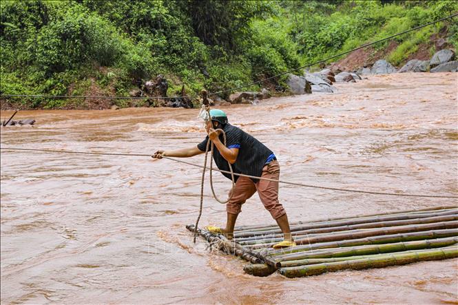 Anh Sùng A Sinh, bản Huổi Lích 1 qua suối Nậm Chà bằng bè tre. Ảnh: Xuân Tư - TTXVN