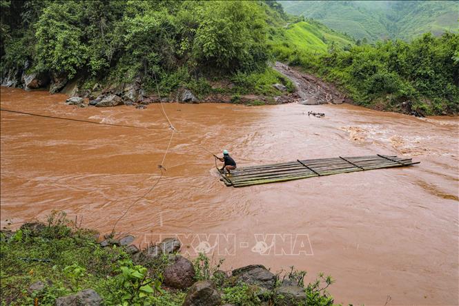 Đi bè tre qua suối lũ luôn tiềm ẩn nguy hiểm. Ảnh: Xuân Tư - TTXVN