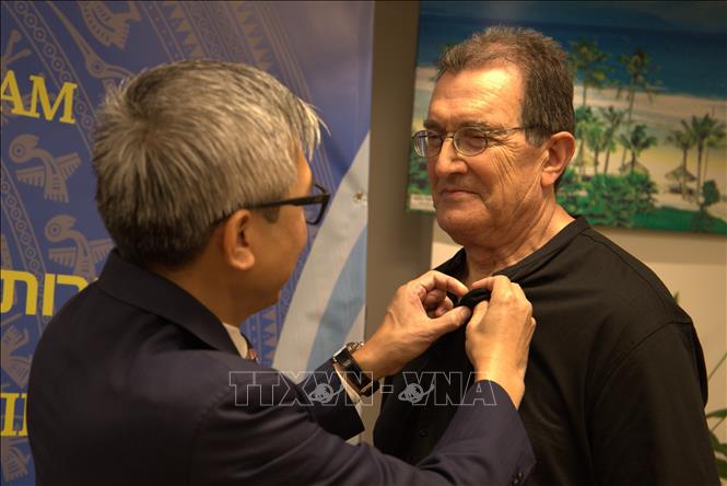Đại sứ Lý Đức Trung đeo huy hiệu Việt Nam cho Giáo sư Benjamin Peretz thuộc Đại học Tel Aviv, người có 16 bức ảnh đen trắng trưng bày tại triển lãm. Ảnh: Thanh Bình - PV TTXVN tại Israel 