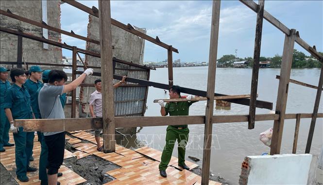 Các lực lượng chức năng phường Giá Rai (tỉnh Cà Mau) giúp dân tháo dỡ, di dời tài sản ra khỏi khu vực sạt lở. Ảnh: TTXVN phát