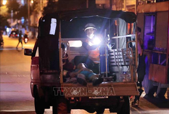 Lực lượng chức năng đưa bị thương ra khỏi hiện trường vụ cháy. Ảnh: Phạm Tuấn Anh - TTXVN