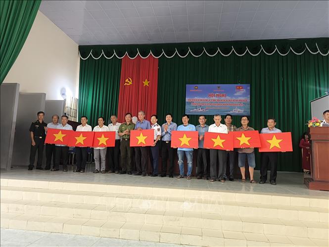 Tặng cờ tổ quốc cho ngư dân vùng biển. Ảnh: Huỳnh Phúc Hậu - TTXVN