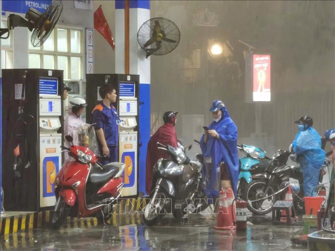 Người dân di chuyển vào trong cây xăng, để tránh mưa giông gió giật. Ảnh: Thanh Tùng - TTXVN 