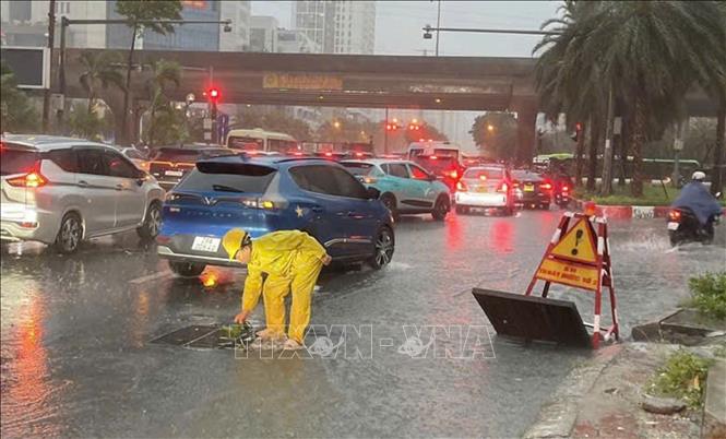 Công nhân Công ty TNHH MTV Thoát nước Hà Nội khẩn trương ứng trực kịp thời tiêu thoát nước trên đường Dương Đình Nghệ. Ảnh: Nguyễn Thắng - TTXVN