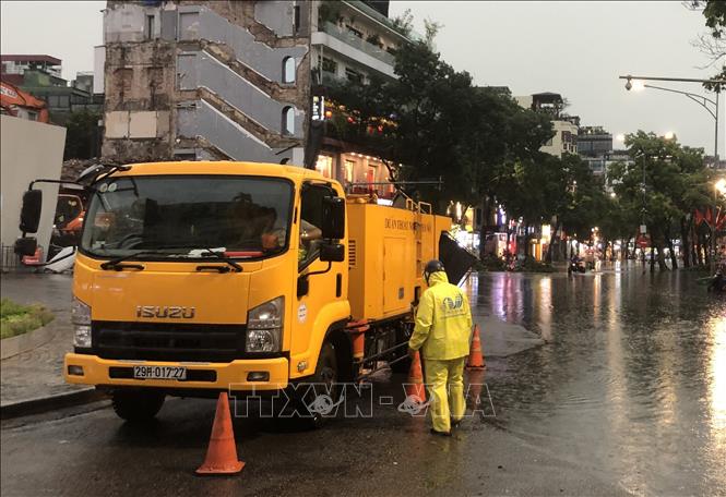 Công nhân Công ty TNHH MTV Thoát nước Hà Nội khẩn trương ứng trực kịp thời tiêu thoát nước trên đường Đinh Tiên Hoàng. Ảnh: Nguyễn Thắng - TTXVN