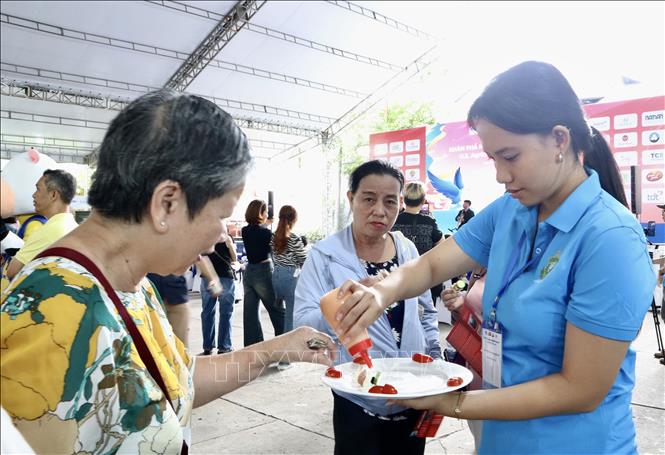 Mời khách quan dùng thử thực phẩm tại Chương trình “Khám phá nông nghiệp Hoa Kỳ”. Ảnh: Xuân Anh -TTXVN