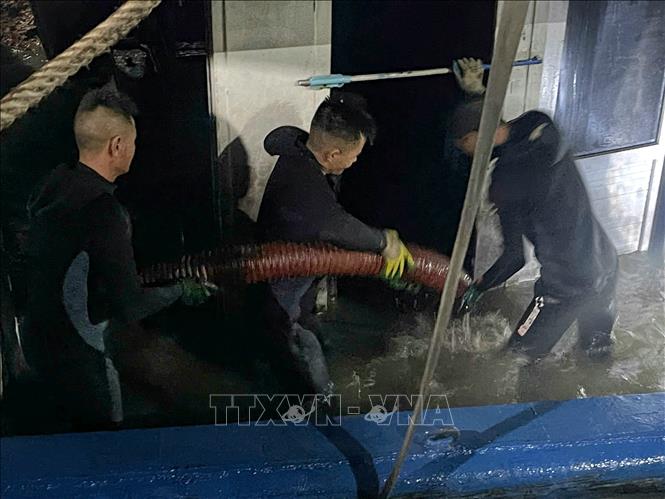 Các lực lượng tiến hành bơm hút nước ra khỏi tàu trước khi lai dắt. Ảnh: Thanh Vân-TTXVN 