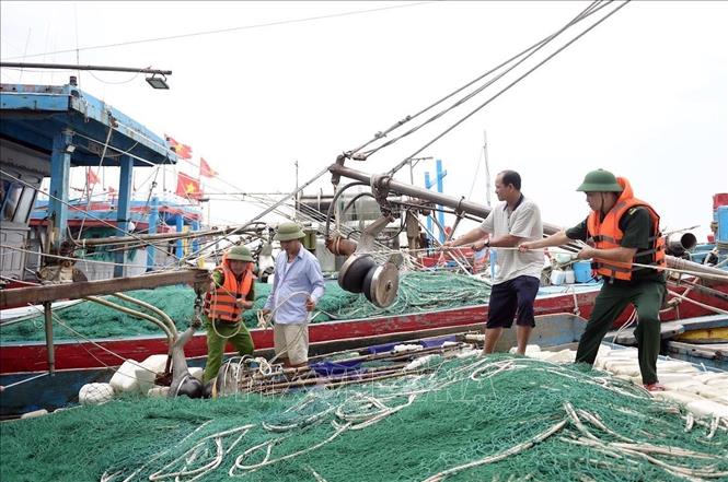 Lực lượng chức năng hướng dẫn, giúp ngư dân xã Hải Thịnh (Ninh Bình) phòng chống bão. Ảnh: Thái Thuần – TTXVN