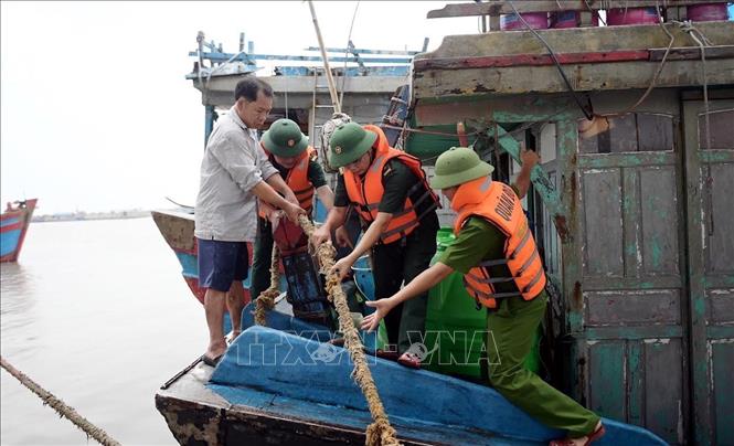 Lực lượng chức năng hướng dẫn, giúp ngư dân xã Hải Thịnh (Ninh Bình) phòng chống bão. Ảnh: Thái Thuần – TTXVN