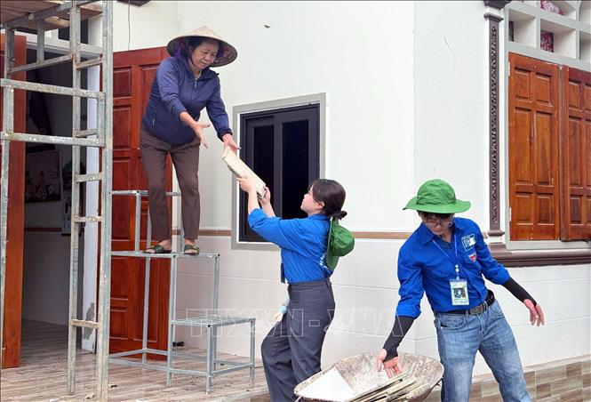 Lực lượng đoàn viên thanh niên giúp đỡ người dân lợp lại nhà sau dông lốc. Ảnh: Công Tường-TTXVN