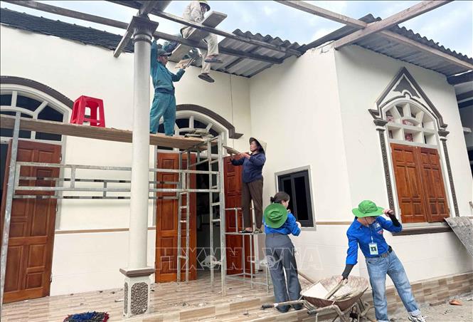 Lực lượng đoàn viên thanh niên giúp đỡ người dân lợp lại nhà sau dông lốc. Ảnh: Công Tường-TTXVN