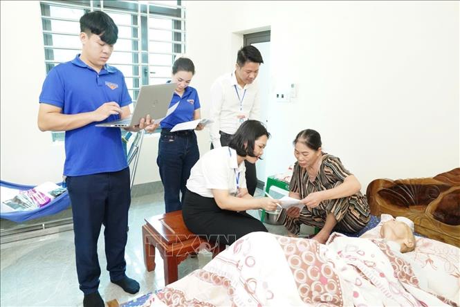 Cán bộ, công chức, viên chức, thanh niên tình nguyện xã Trường Tân đến tận nhà hỗ trợ giải quyết thủ tục hành chính cho người dân không đủ sức khỏe đến Trung tâm Phục vụ hành chính công. Ảnh: TTXVN phát 
