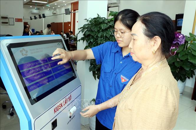 Thanh niên tình nguyện xã Trường Tân hướng dẫn người dân lấy số thứ tự để giải quyết thủ tục hành chính
Ảnh: Mạnh Tú - TTXVN 