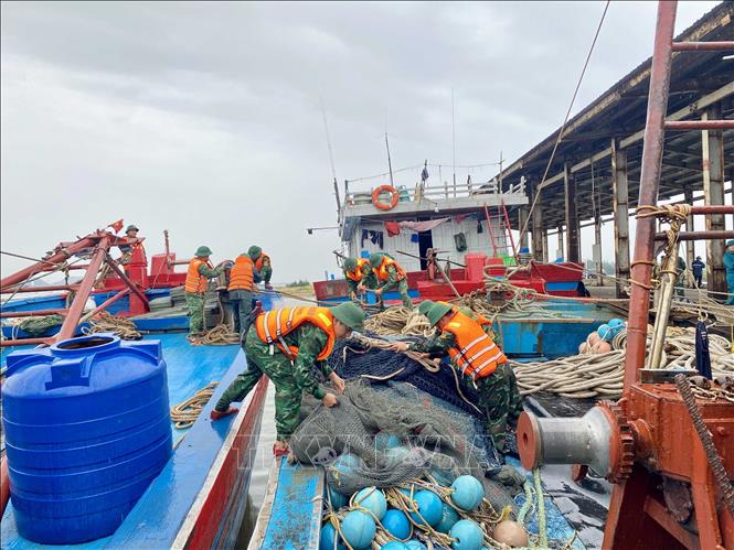 Bộ đội biên phòng hỗ trợ ngư dân gia cố, chằng néo tàu thuyền. Ảnh: Hữu Quyết - TTXVN