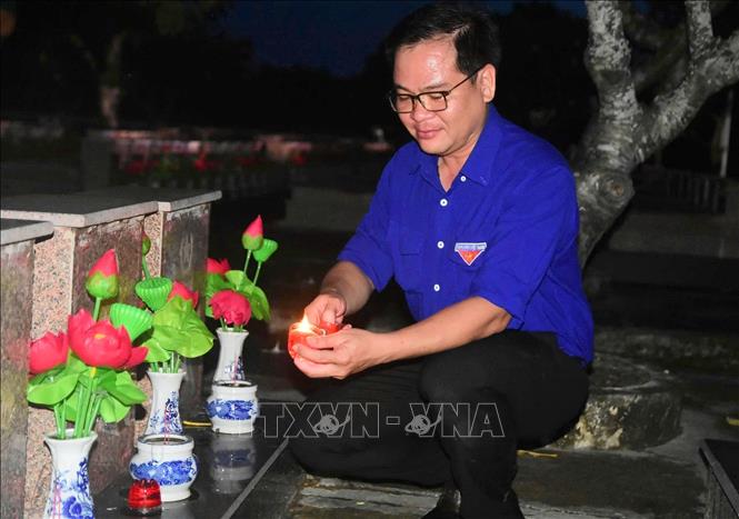 Đoàn viên, thanh niên tỉnh An Giang thắp nến tại phần mộ các Anh hùng liệt sĩ. Ảnh: TTXVN phát
