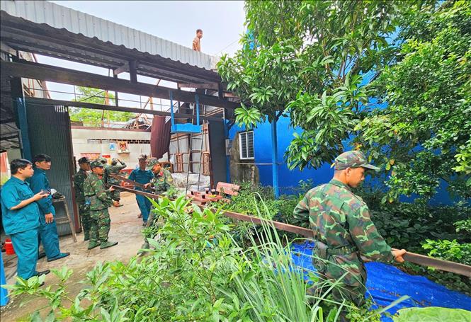 Lực lượng chức năng phường Bình Đức (tỉnh An Giang) hỗ trợ người dân thu dọn nhà cửa bị ảnh hưởng của bão số 3, sớm ổn định cuộc sống. Ảnh: Công Mạo-TTXVN