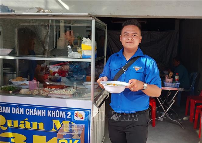 Bí thư Chi đoàn khóm 2 (phường Giá Rai) Trịnh Trọng Bình bưng tô mì phục vụ khách đến ăn sáng. Ảnh: Tuấn Kiệt – TTXVN.
