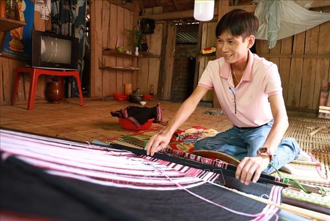 Du khách trực tiếp trải nghiệm dệt thổ cẩm ở làng nghề Xí Thoại. Ảnh: Xuân Triệu - TTXVN