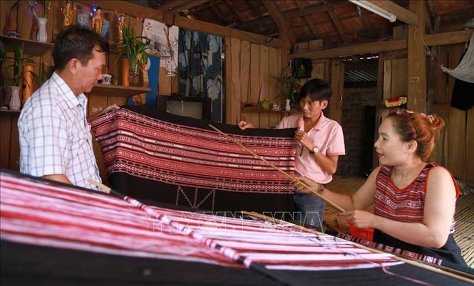 Nghệ nhân dệt thổ cẩm ở Xí Thoại giới thiệu cho du khách về hoa văn thổ cẩm. Ảnh: Xuân Triệu – TTXVN