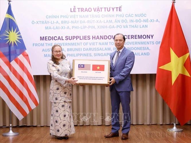 Năm Chủ tịch ASEAN 2020, Việt Nam đã thúc đẩy Cộng đồng ASEAN gắn bó và ứng phó hữu hiệu, kịp thời trước các thách thức chưa từng có của đại dịch COVID-19, giữ vững đoàn kết, duy trì đà liên kết của ASEAN. Trong ảnh: Thứ trưởng Bộ Ngoại giao Nguyễn Quốc Dũng trao tượng trưng hỗ trợ vật tư y tế của Chính phủ và nhân dân Việt Nam cho Chính phủ và nhân dân Malaysia phòng, chống COVID-19, chiều 18/5/2020. Ảnh: Văn Điệp - TTXVN