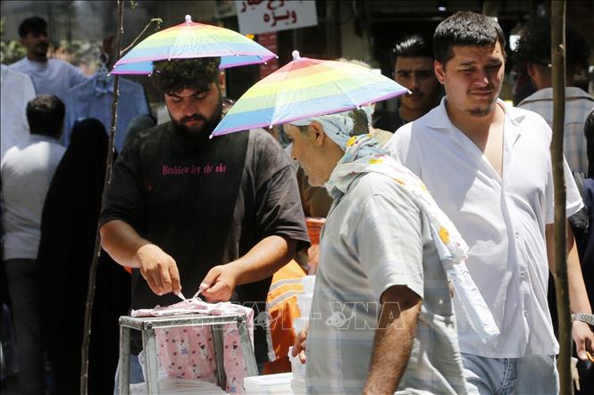 Người dân dùng ô che nắng tại Tehran, Iran ngày 22/7/2025. Ảnh: THX/TTXVN