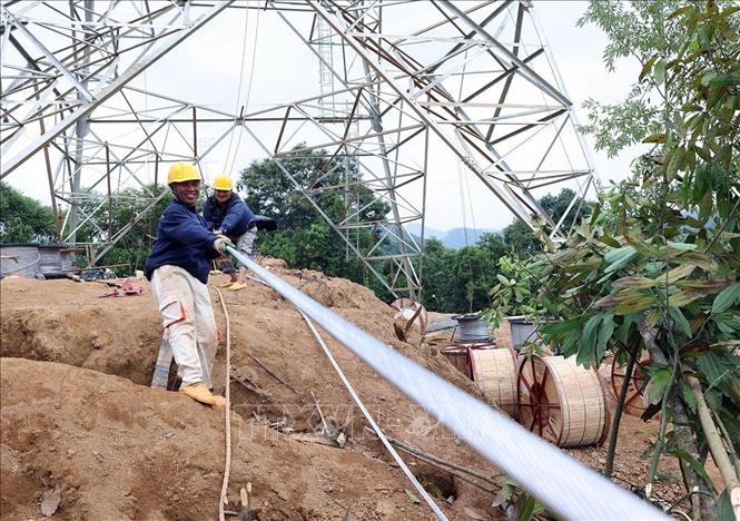 Công nhân triển khai kéo cáp điện lên cột ở vị trí cột số 18, thuộc địa bàn xã Xuân Quang, tỉnh Lào Cai. Ảnh: Vũ Sinh - TTXVN